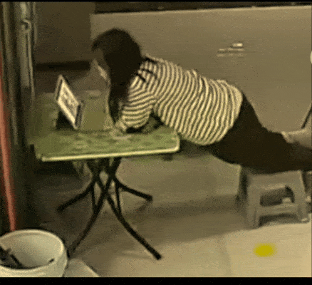 a girl fell under the table while strechingherself to watch a tablet